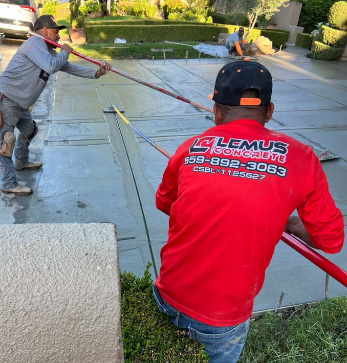 Licensed concrete professionals from Lemus Concrete LLC using a bull float to create a smooth, level finish on a large-scale residential concrete pour.