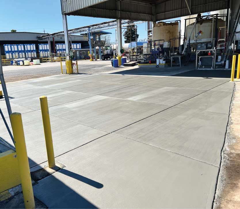 Industrial-grade commercial concrete services showing a large, reinforced concrete slab with a professional broom finish outside an industrial facility in the Central Valley.