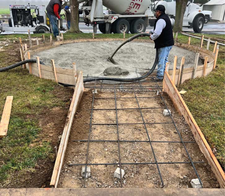 Lemus Concrete LLC crew performing a concrete pour for a circular residential foundation featuring a reinforced rebar grid and wooden formwork in the Central Valley.